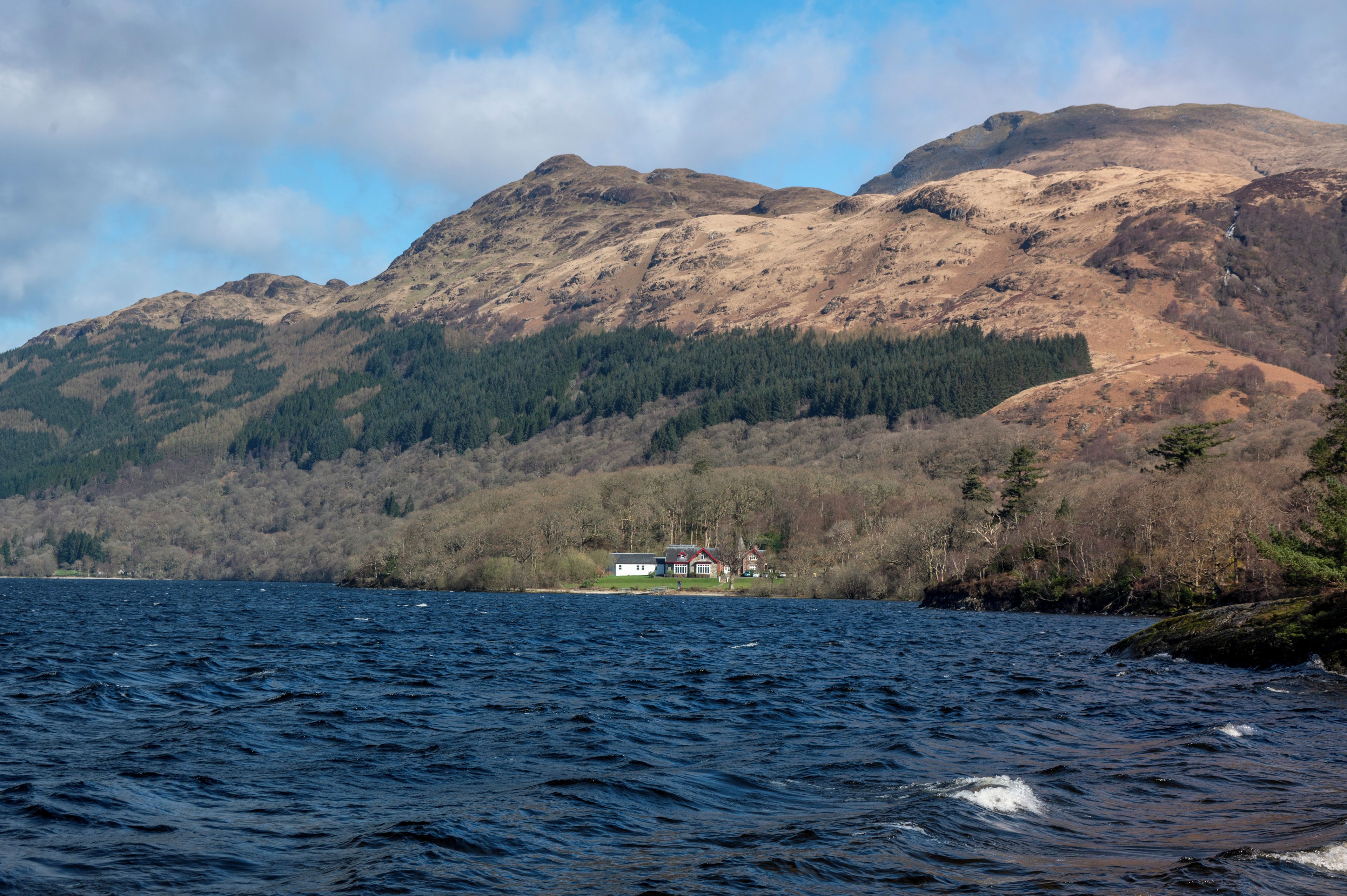 A house by a lake with mountains in the background.