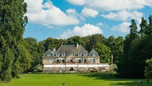 A large, historic building with multiple windows and a covered front porch, surrounded by lush greenery. - Hotel Parc des Eaux-Vives (Geneva)