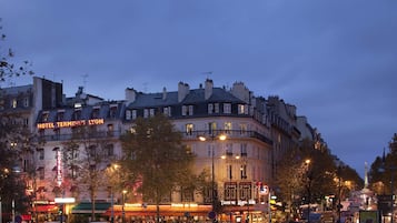 Un bâtiment historique, reconnaissable à son imposante enseigne « HÔTEL TERMINUS LYON », entouré d’arbres et de lampadaires.