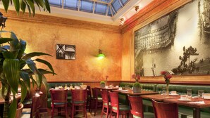Un restaurante con cabinas verdes, mesas de madera y un gran mural en la pared.