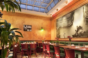 Un restaurante con cabinas verdes, mesas de madera y un gran mural en la pared.
