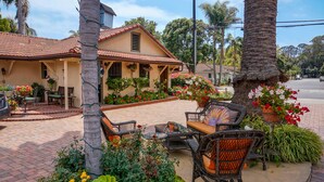 Une maison dotée d’un patio aménagé avec des meubles en osier et des plantes en pot.