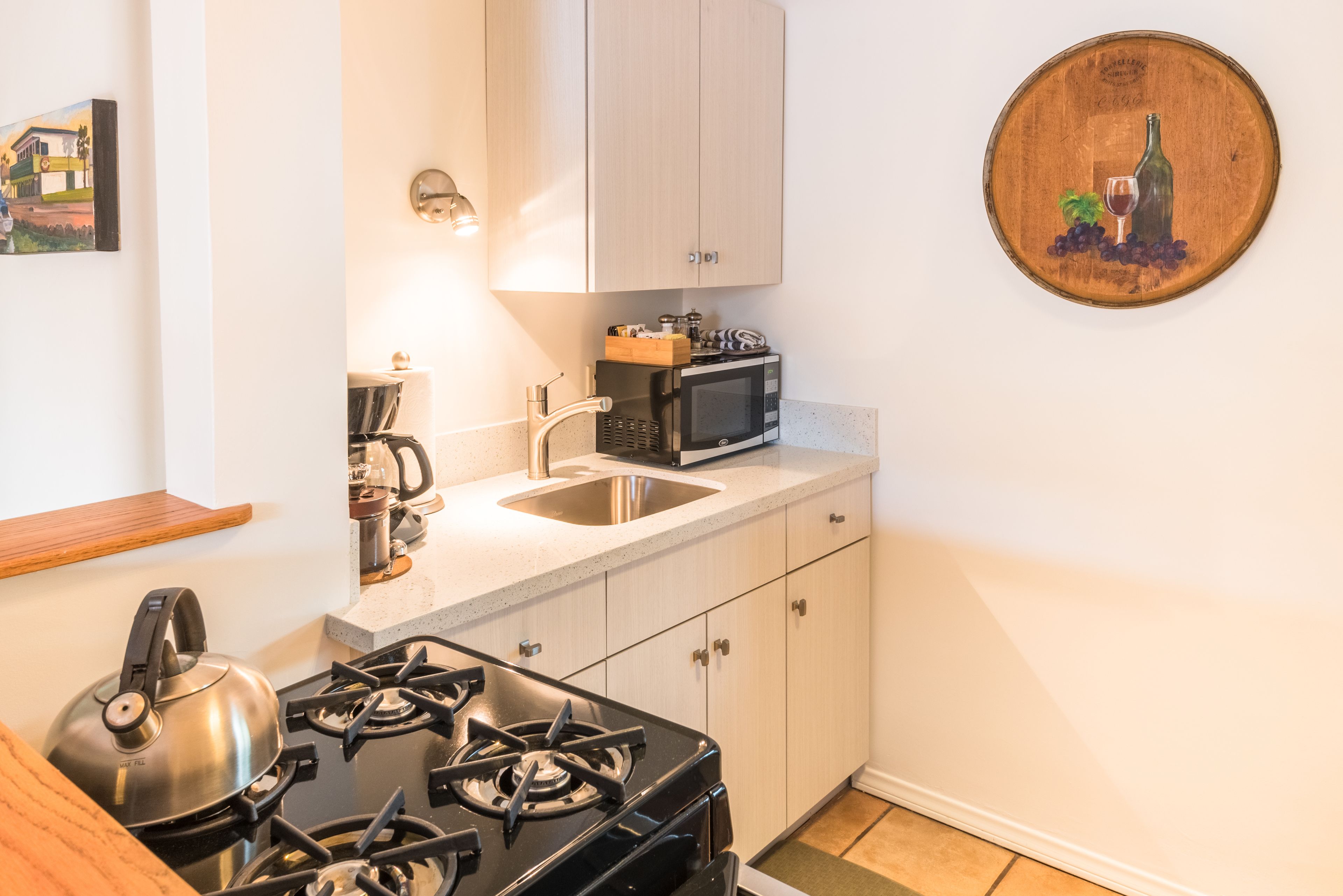 A compact kitchen with a gas stove, microwave, sink, and wooden cabinets.