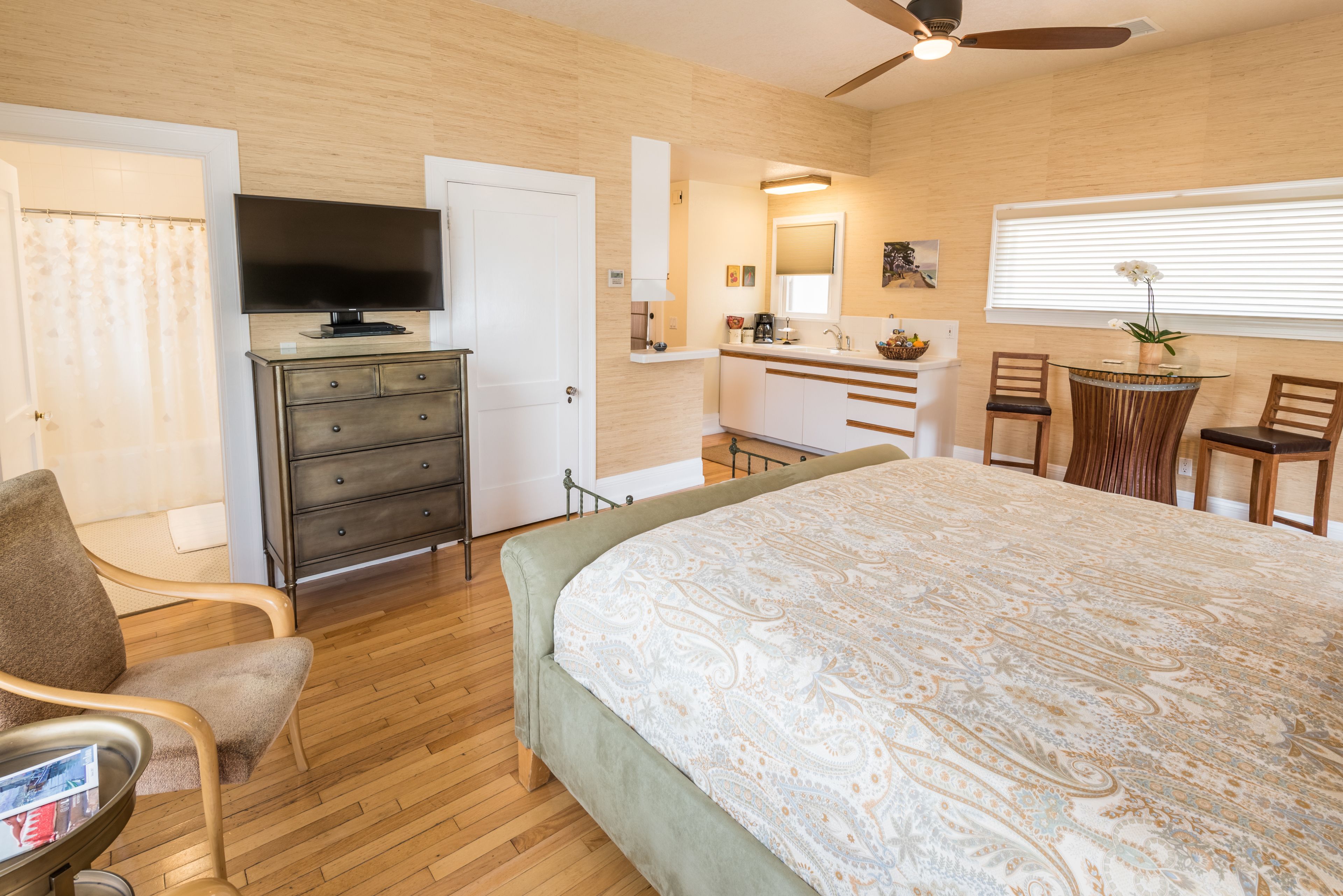 Un dormitorio con cama, cómoda, televisor, escritorio y silla.
