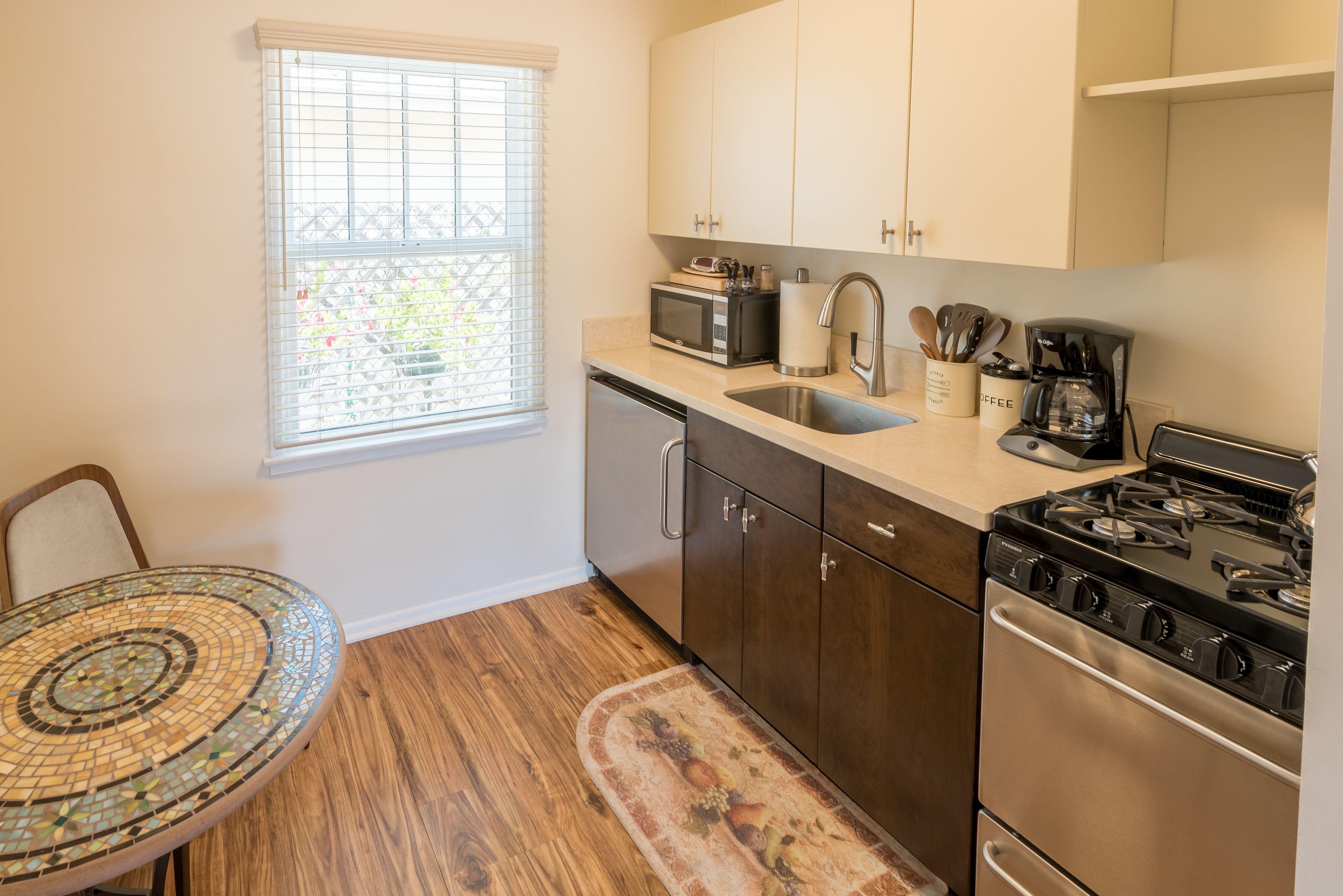 A kitchen with a microwave, stove, sink, and cabinets.