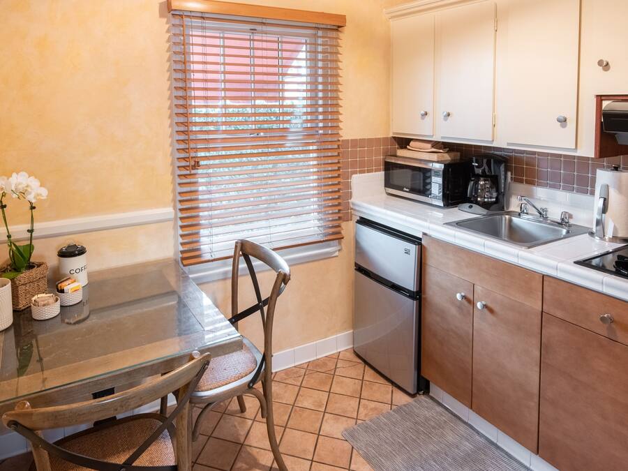 Una cocina compacta con comedor, que incluye un microondas, cafetera y un lavamanos.