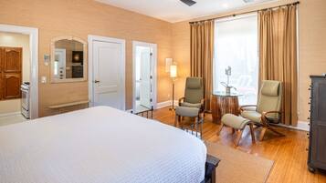 Een hotelkamer met een groot bed, twee stoelen, een bijzettafeltje, een lamp en een kledingkast.