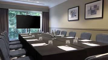 A conference room with a long table, chairs, a TV, and framed pictures on the wall.