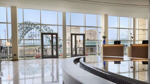 A hotel lobby with large windows, a reception desk, and a water feature. - Hilton Newcastle Tyne Bridge (Gateshead)
