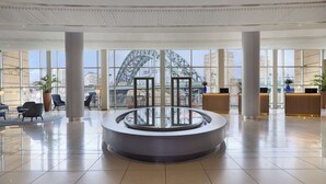 A spacious lobby with a central glass table, large windows, and a view of a bridge. - Hilton Newcastle Tyne Bridge (Gateshead)