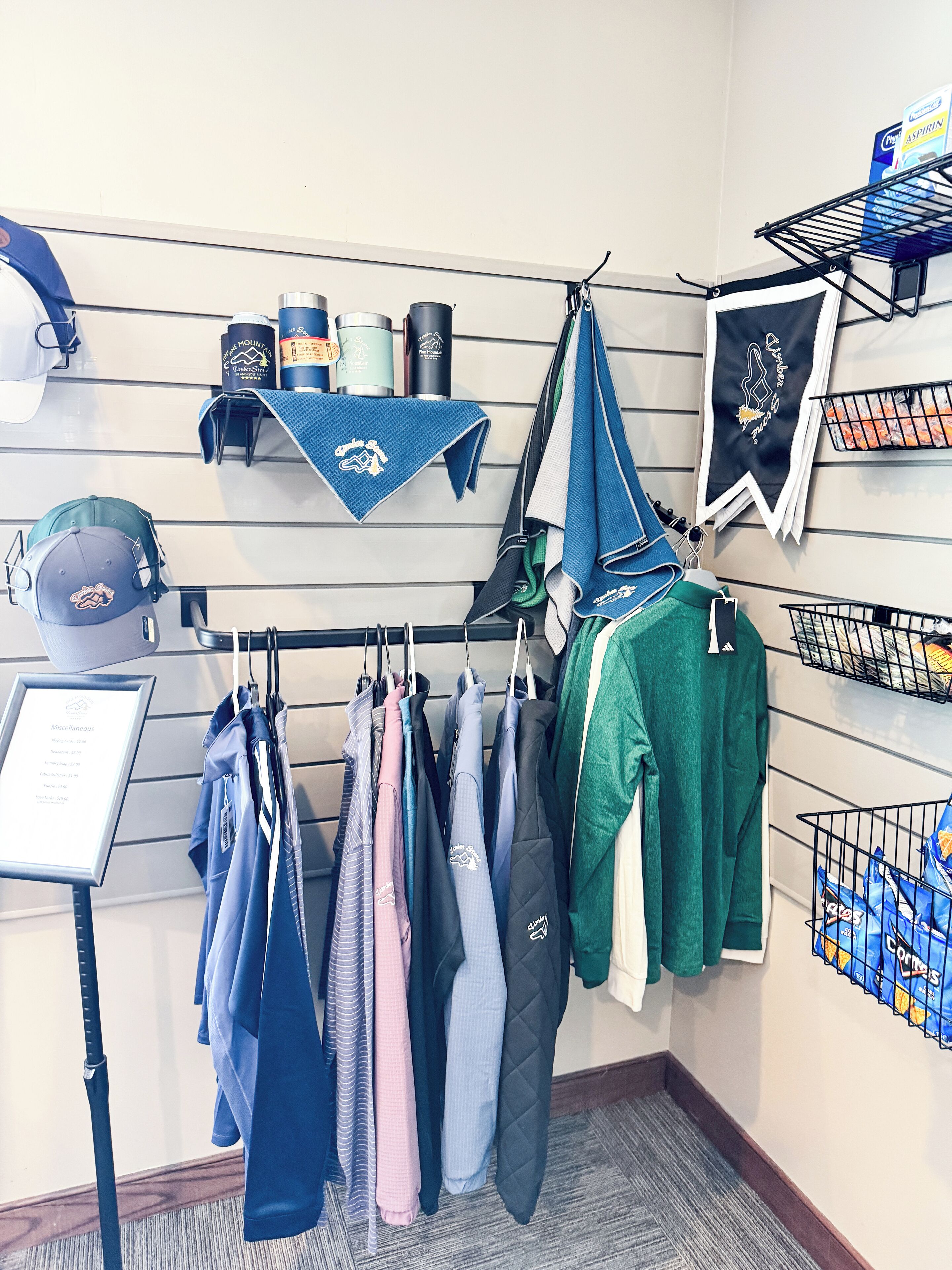 A clothing rack with various garments, a display of toiletries, and a framed sign with text.