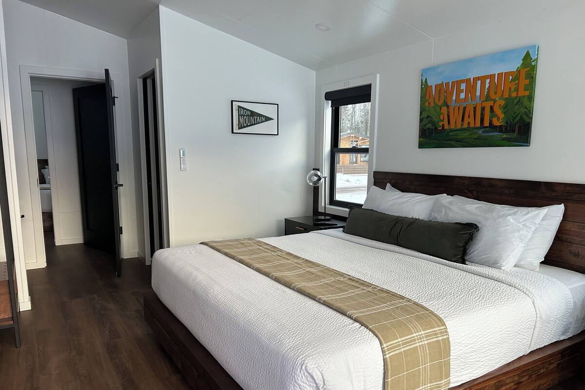 A bedroom with a large bed, a nightstand, a window, and a door.