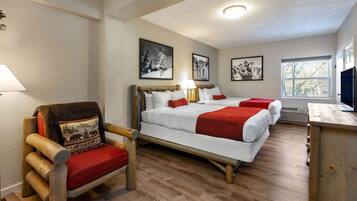 A hotel room with a wooden bed, a chair with a red cushion, and a television on a wooden stand.