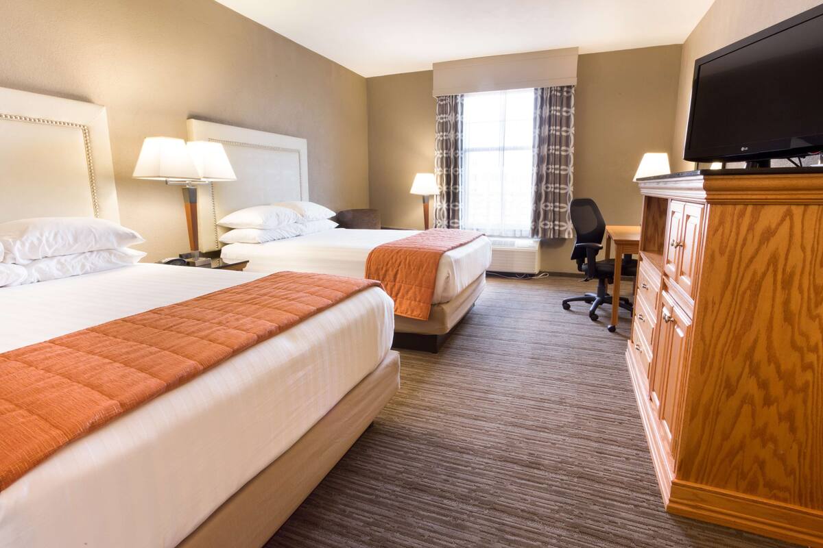 Une chambre d’hôtel avec deux lits, une télévision, un bureau et une chaise.