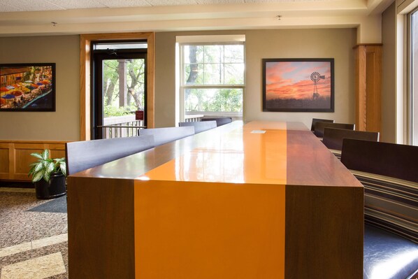A conference room with a long table, chairs, and a potted plant.