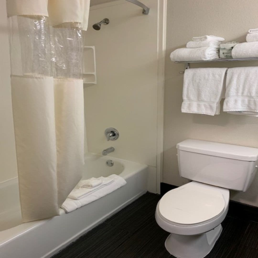 A modern bathroom with a bathtub, toilet, and a towel rack with folded towels.
