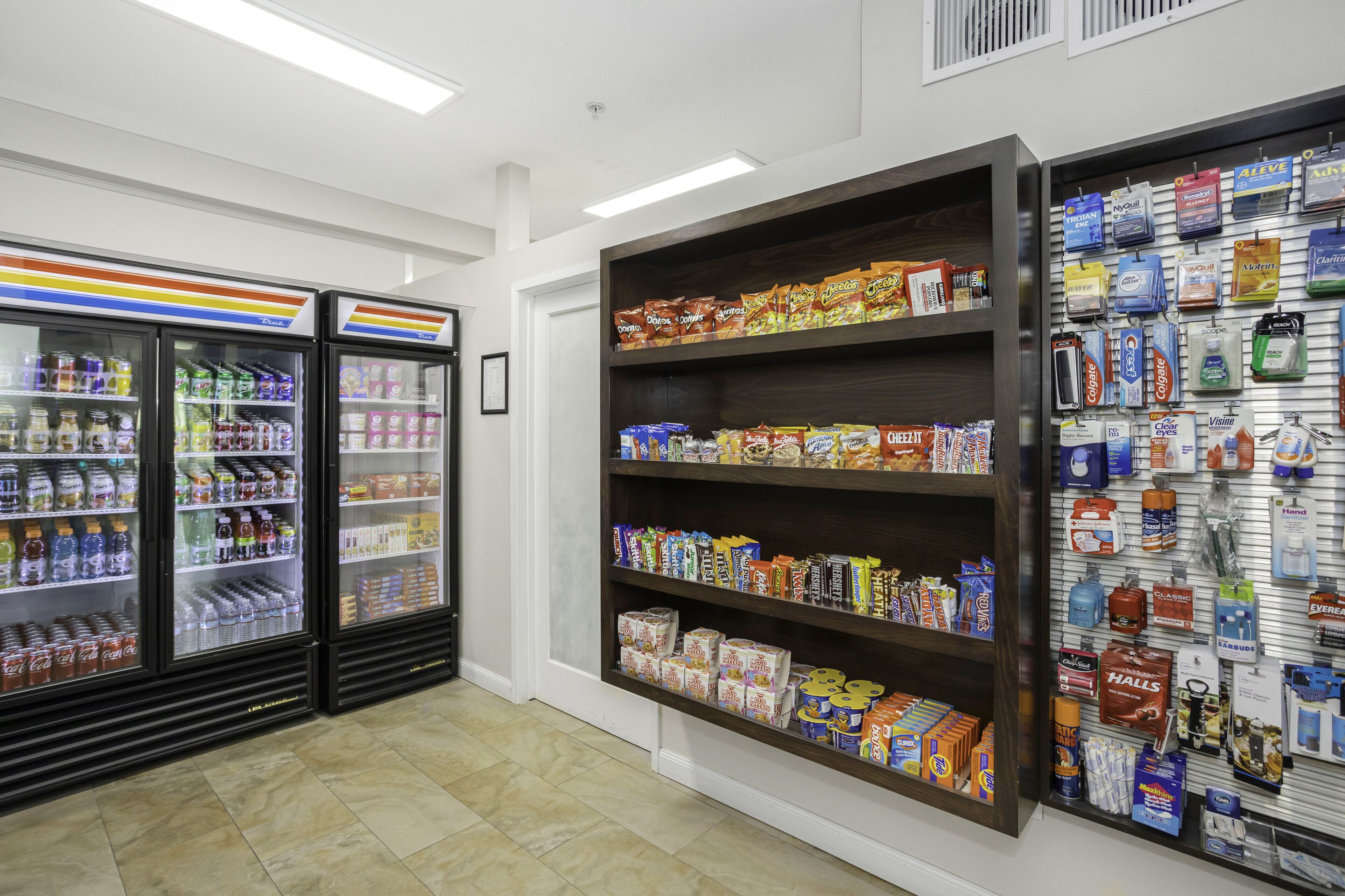 Un magasin doté de présentoirs réfrigérés pour les boissons, d’étagères remplies de collations et de boissons, et d’un assortiment de produits de toilette.