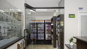 Un pasillo con una pared de vidrio que presenta un cuadro de paisaje, un letrero de Bright Side Market y una fila de dispensadores de bebidas.