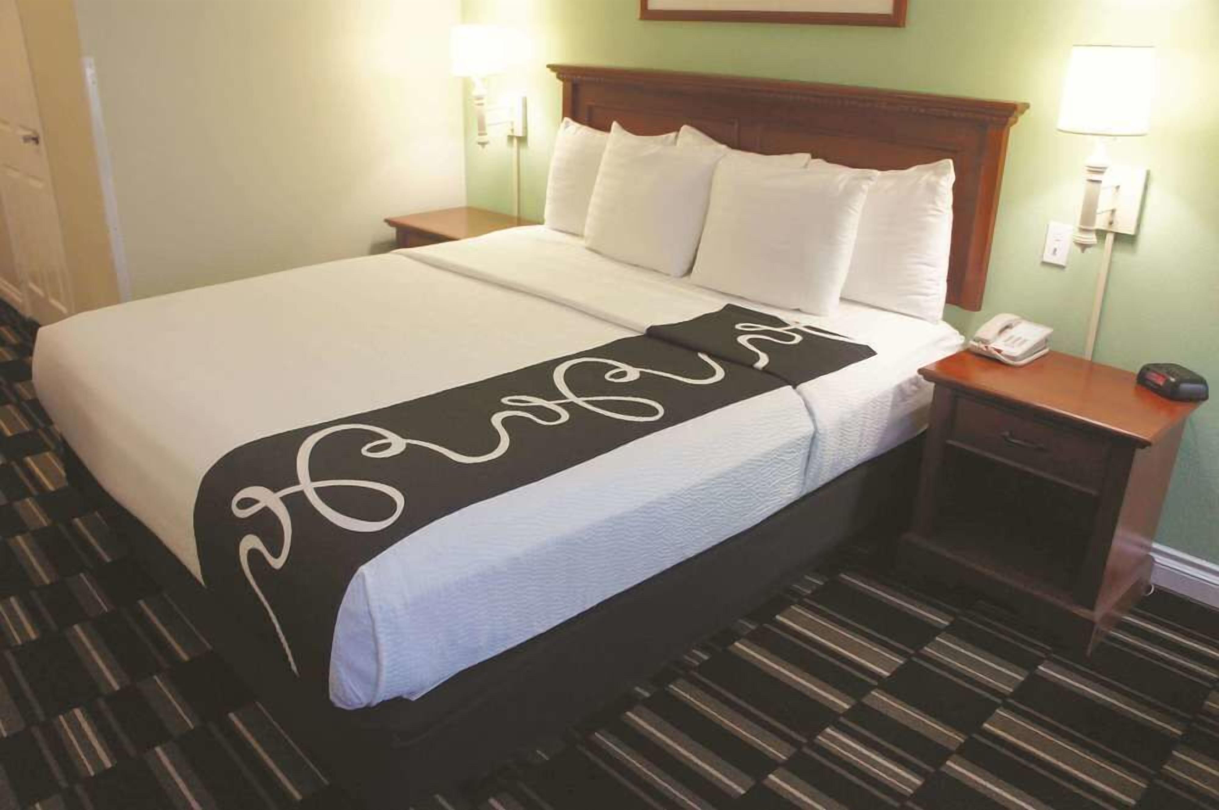 A hotel room with a bed, a nightstand, a lamp, and a telephone.