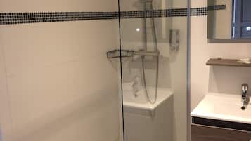 A modern bathroom with a glass-enclosed shower, a white sink, and a mirror above the sink.