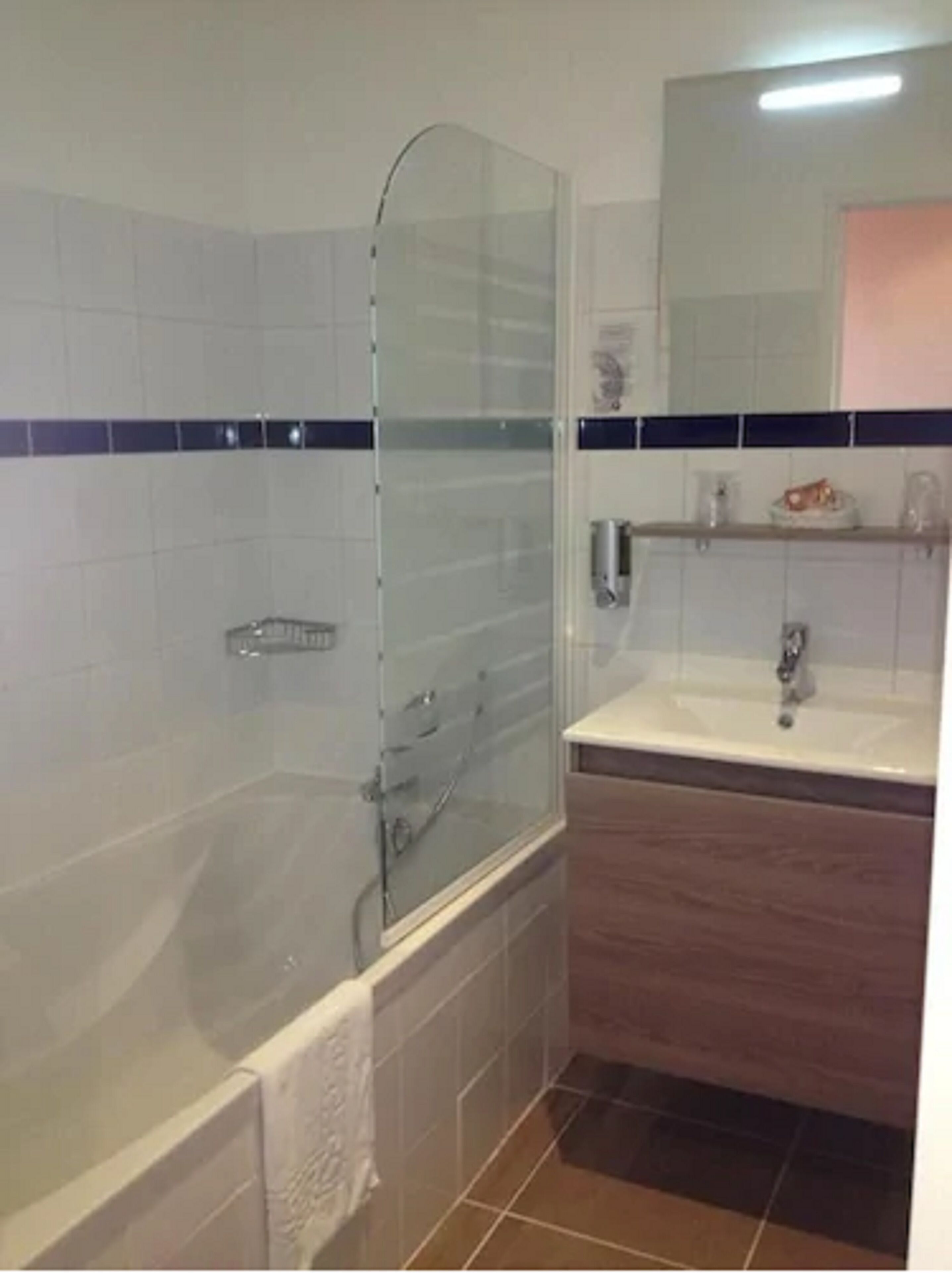 A bathroom with a glass-enclosed shower, a sink, and a mirror.