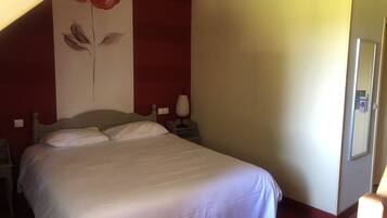 Une chambre à coucher comprenant un lit, une table de chevet, une lampe et un mur orné d’un motif floral.