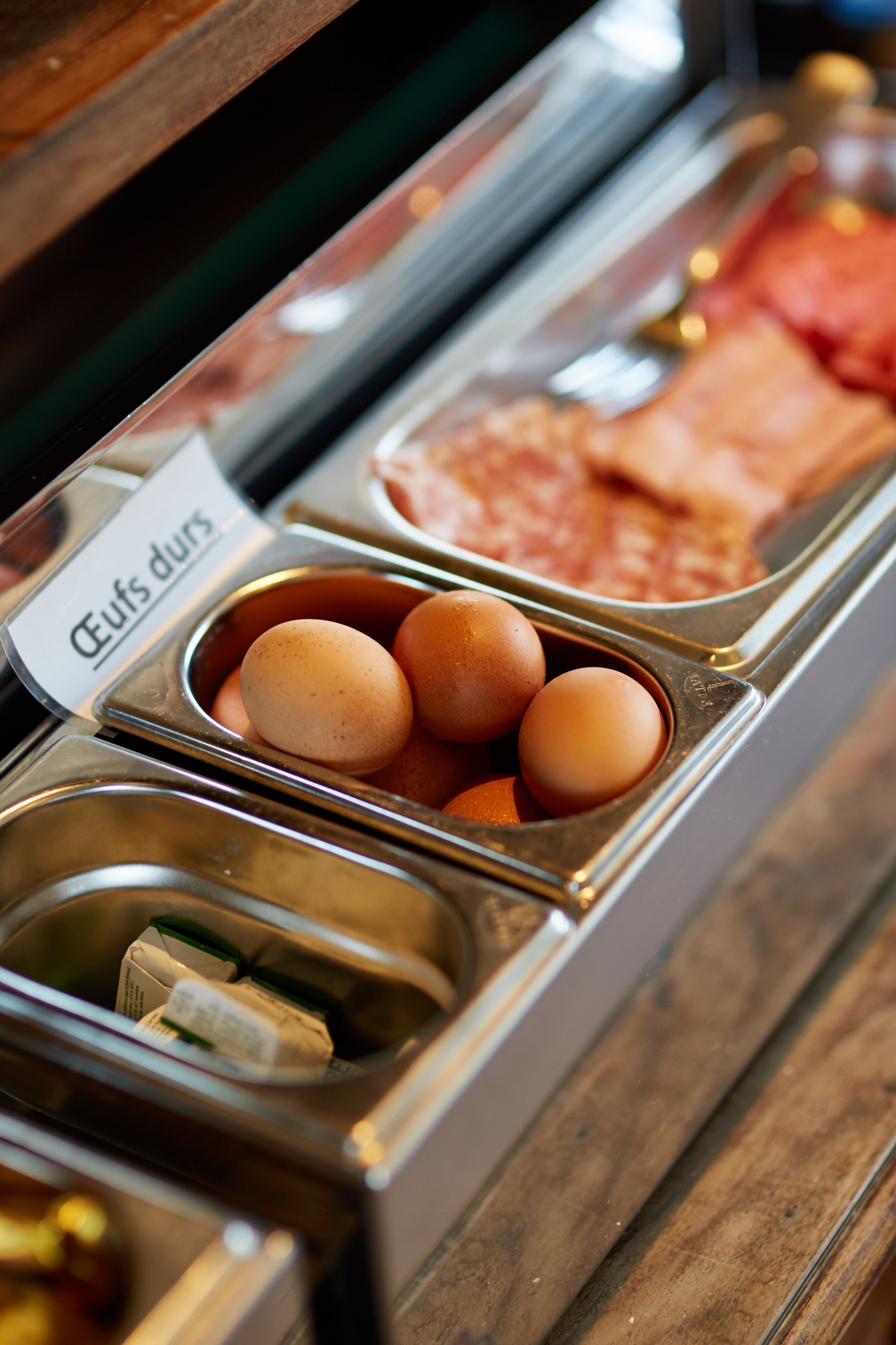 A breakfast buffet with labeled containers for eggs, meat, and milk.