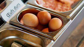 A breakfast buffet with labeled containers for eggs, meat, and milk.