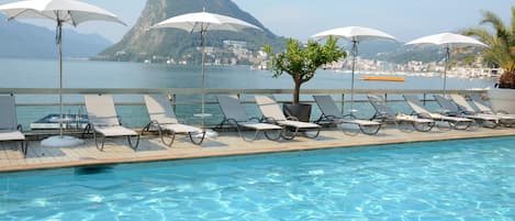 Una piscina al aire libre de temporada, sombrillas