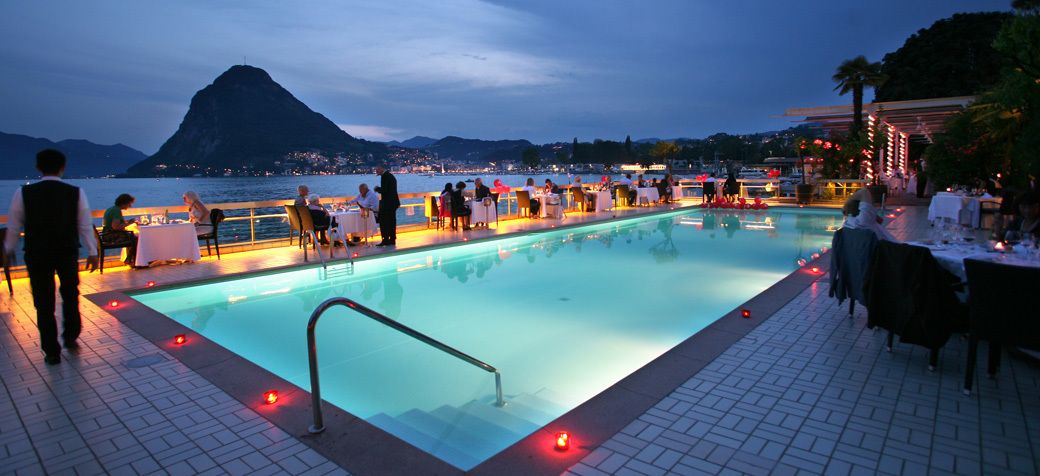 An outdoor swimming pool with a view of a mountain and a cityscape in the background.