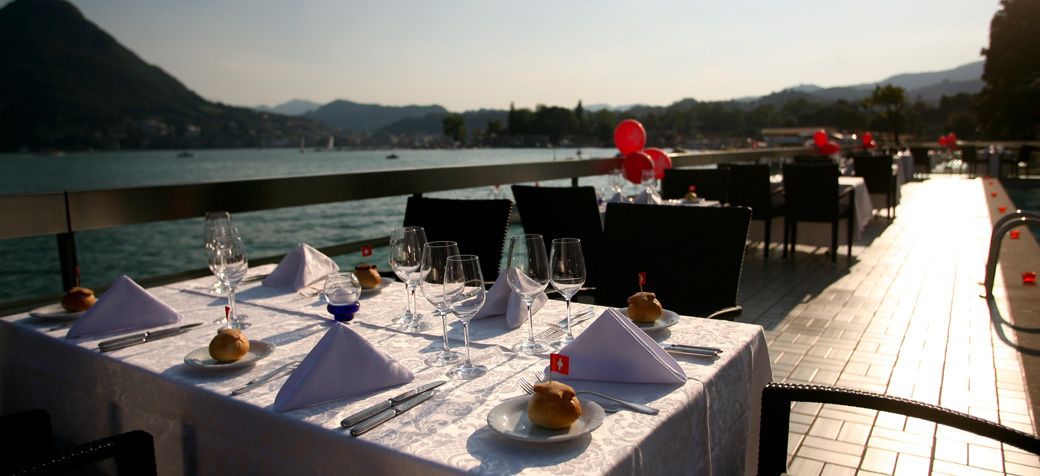 Una mesa lista para comer con vistas al agua y a las montañas.