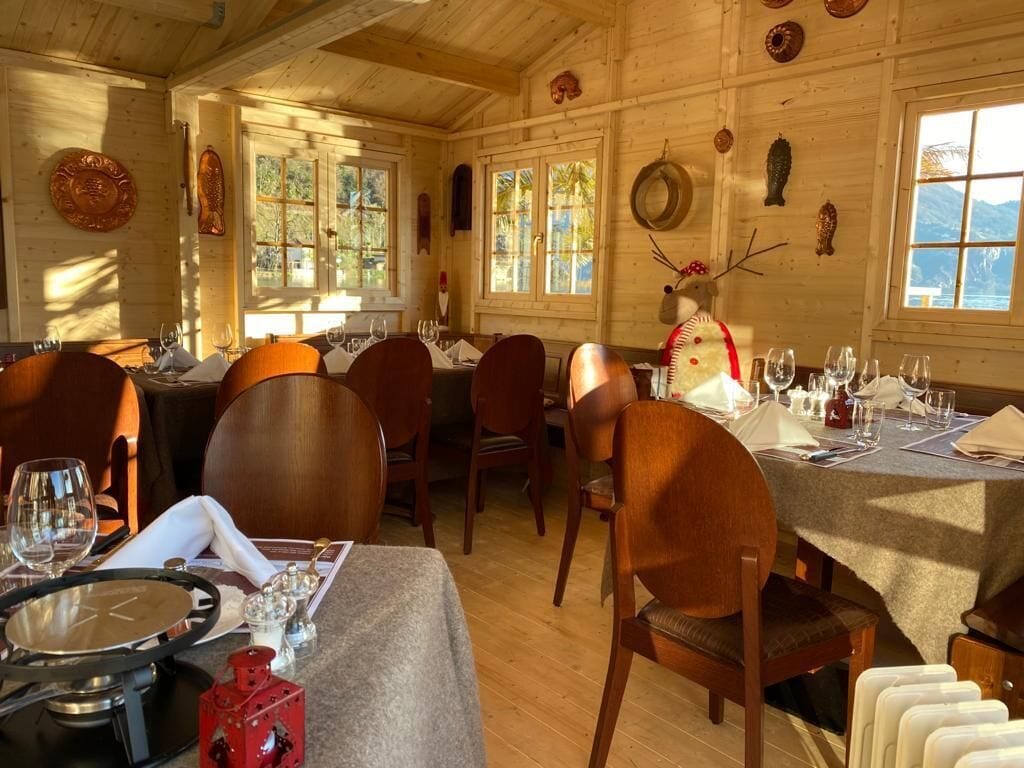 Ein Holzinnenraum mit gedeckten Tischen, Holzstühlen und einer dekorativen Bärenfigur.