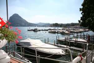 Un puerto deportivo con barcos amarrados, un telón de fondo montañoso y cielo despejado.