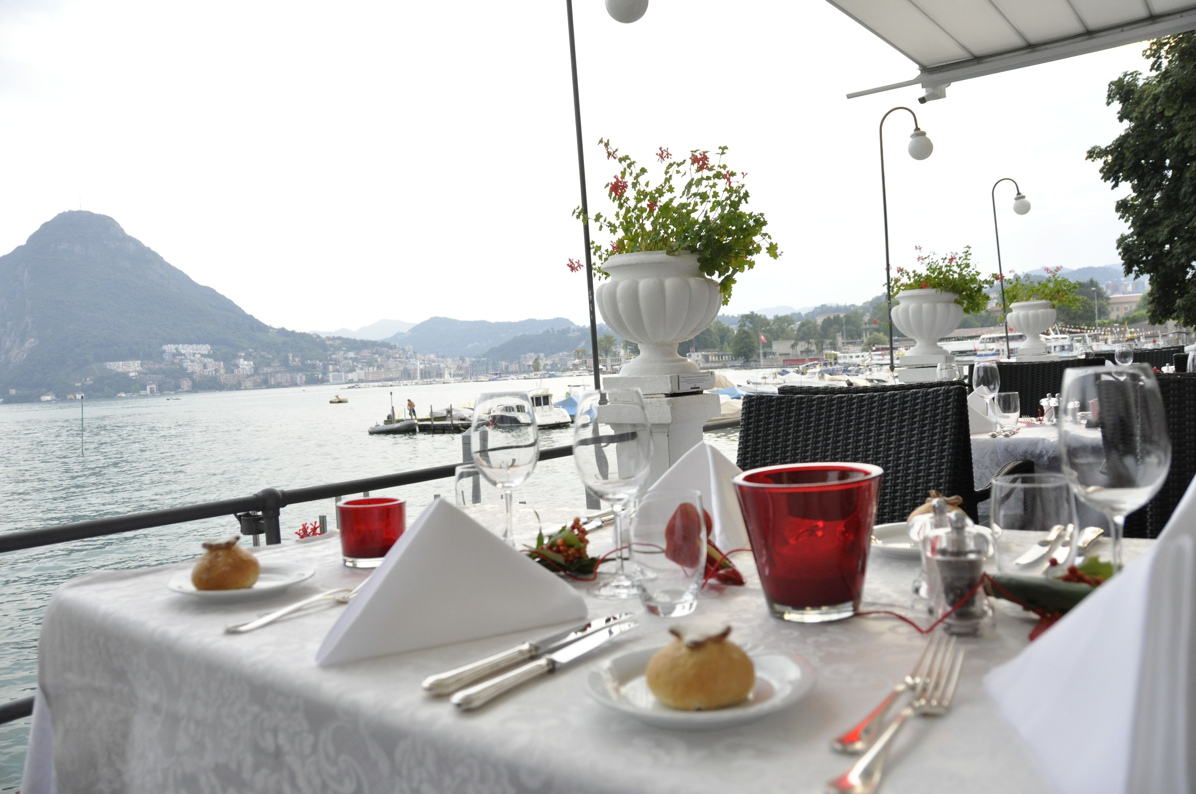 A table set for dining with a view of a body of water and distant mountains.