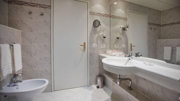 A bathroom with a sink, bidet, and mirror.