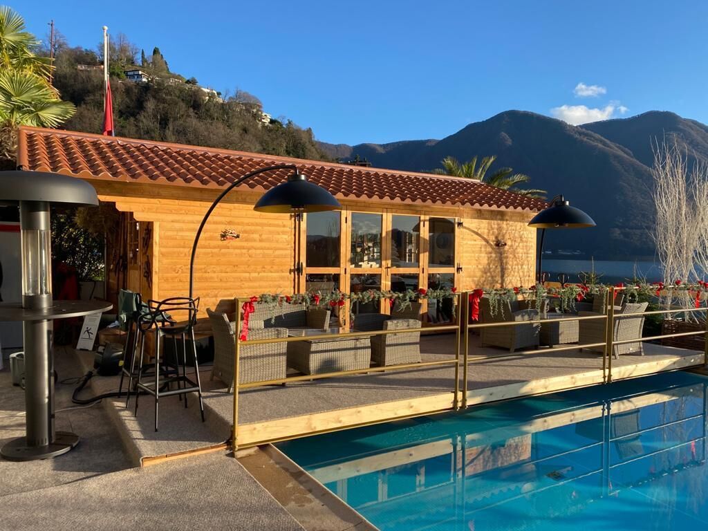 Un edificio in legno con tetto in tegole, una piscina e un'area relax all'aperto.