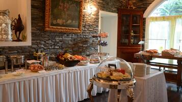 Un'impostazione buffet con diversi cibi, un quadro appeso al muro e uno sfondo con texture in pietra.