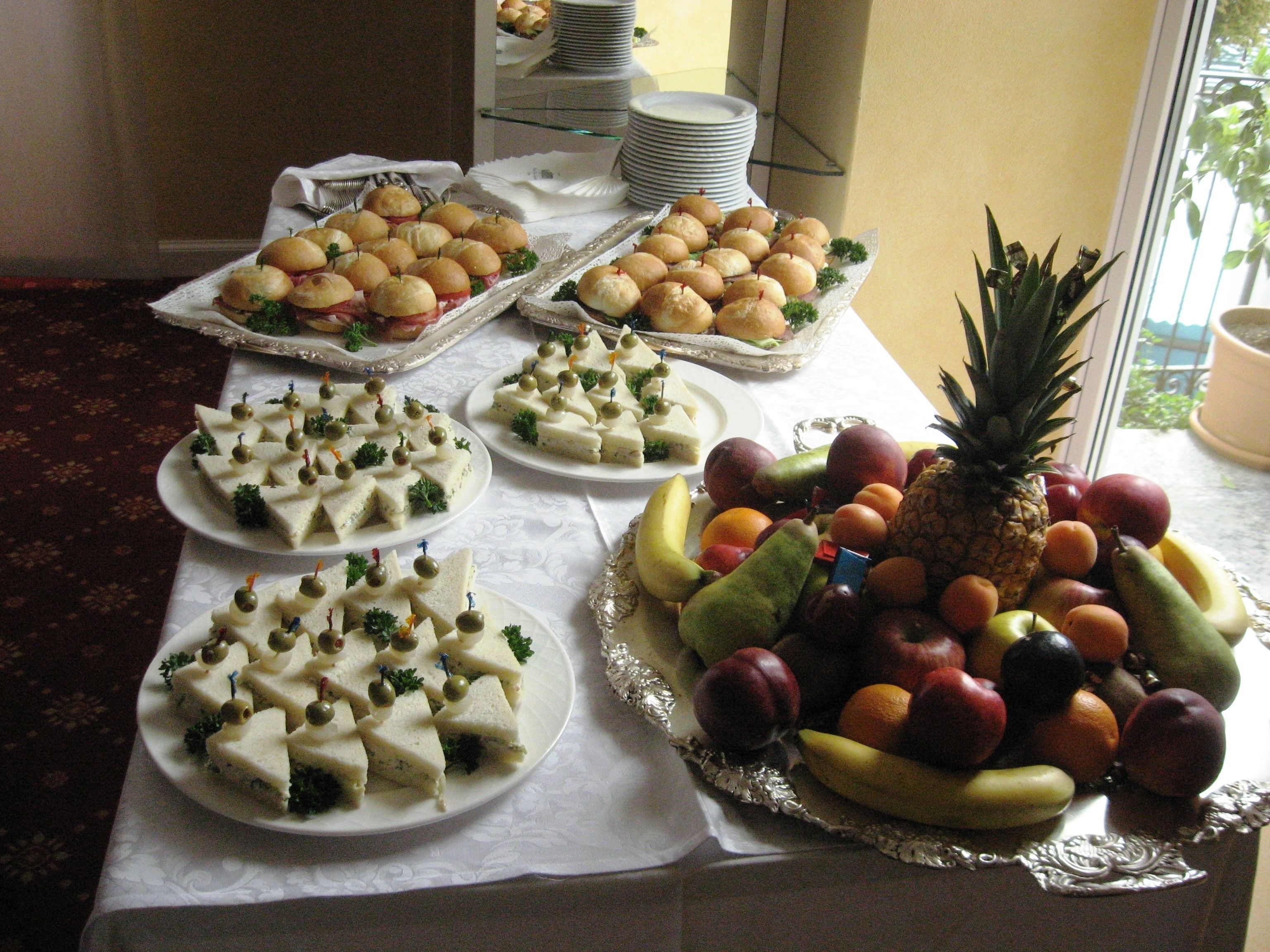 Une table de buffet proposant divers aliments, notamment des sandwichs, des fruits et d’autres collations.