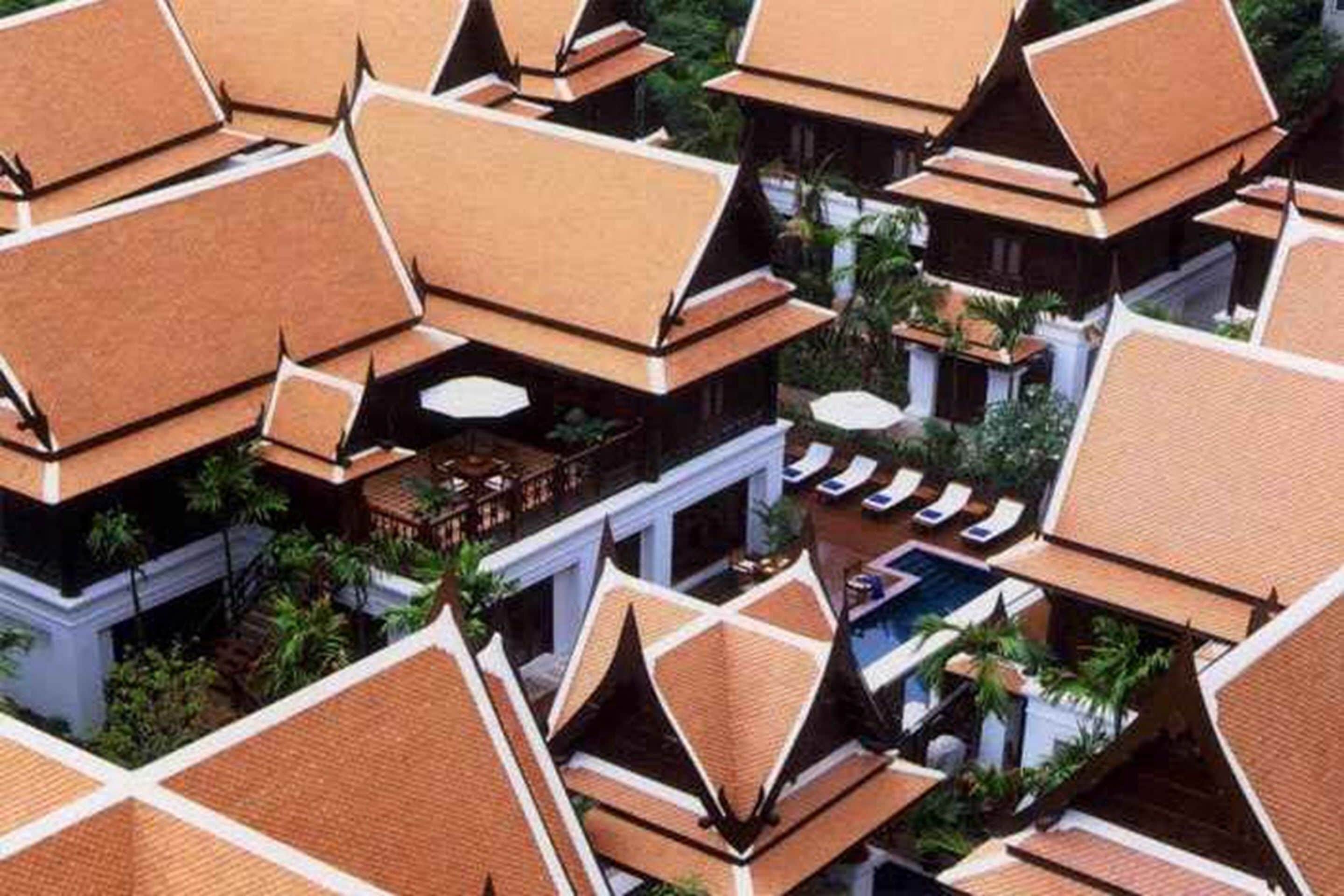 A resort with multiple buildings featuring traditional architecture, including tiered roofs and a swimming pool area.