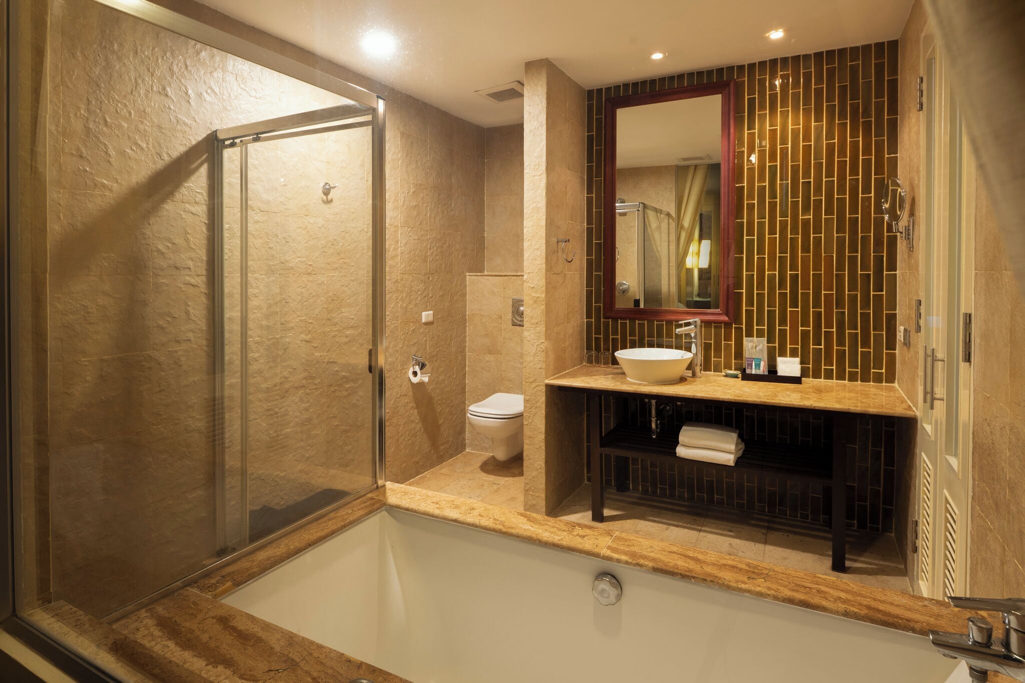 A modern bathroom with a glass-enclosed shower, a freestanding bathtub, and a vanity with a large mirror and sink.