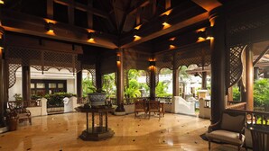 A spacious lobby with a polished marble floor, wooden furniture, and a central decorative fountain.