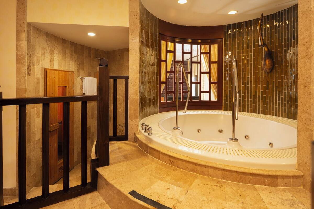 Une salle de bain moderne avec une grande baignoire sur pieds, une porte en bois et une vue par une fenêtre ornée de rideaux jaunes.