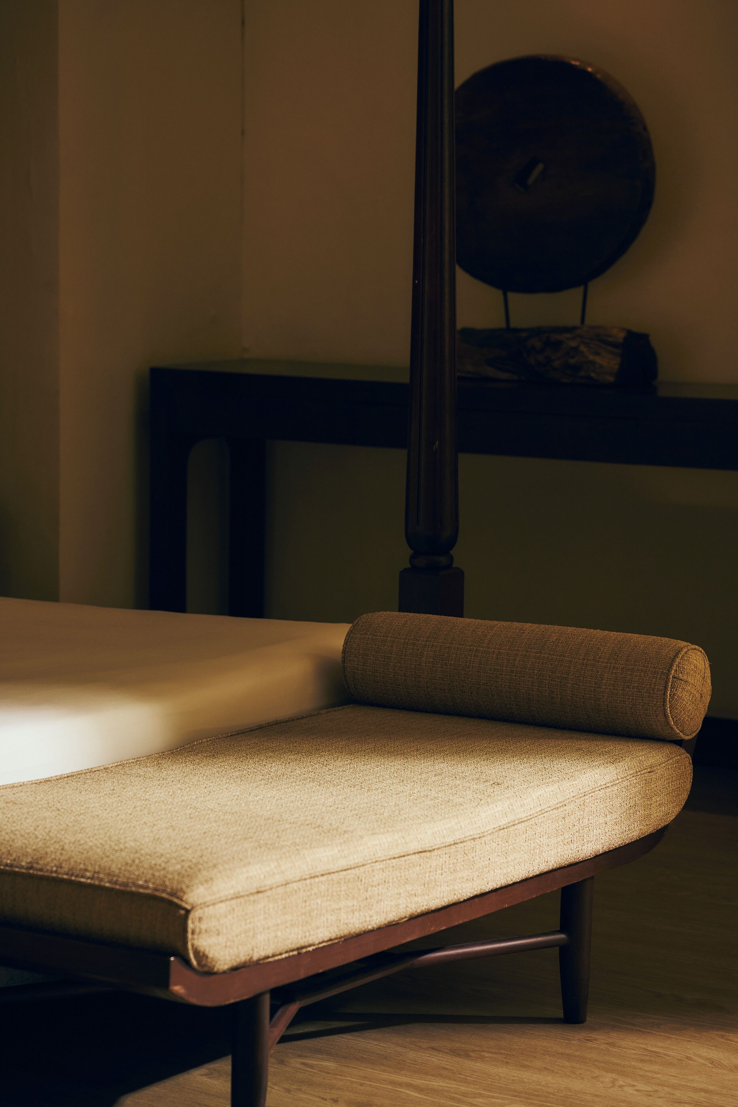 Una silla con asiento y respaldo acolchados, ubicada en una habitación con suelo de madera y una mesa de madera oscura al fondo.