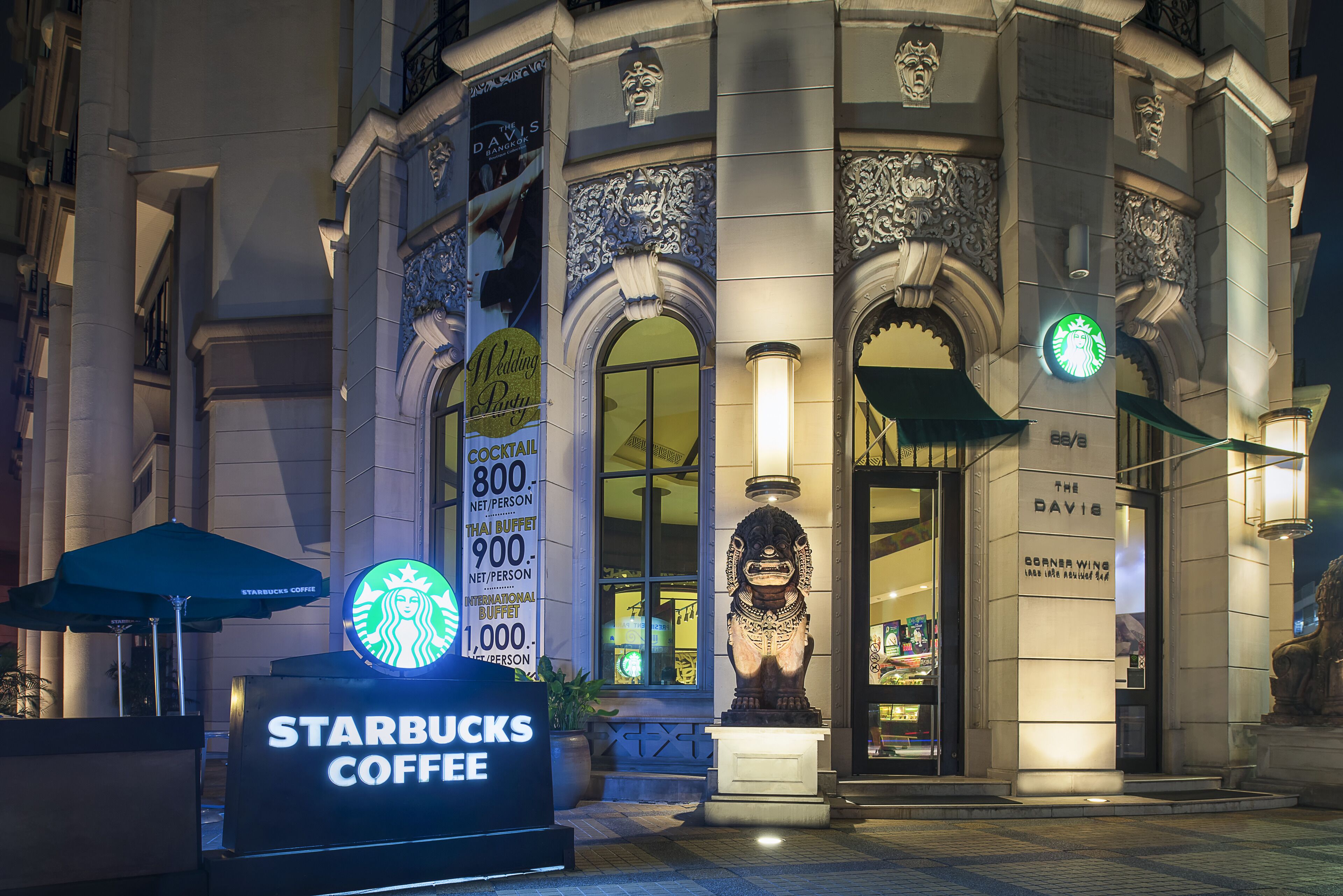 Een Starbucks Coffee bordje voor een gebouw met versierde architectonische details en een standbeeld.