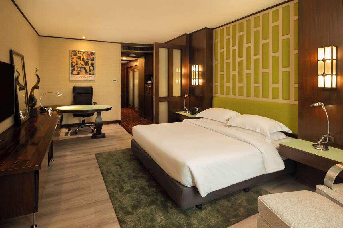 Une chambre d’hôtel avec un grand lit, un bureau avec une chaise, une petite table et un téléviseur.