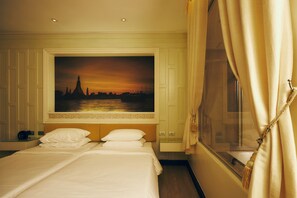 Een hotelkamer met een groot bed, een schilderij van een stadsgezicht, een raam met gordijnen en een nachtkastje.