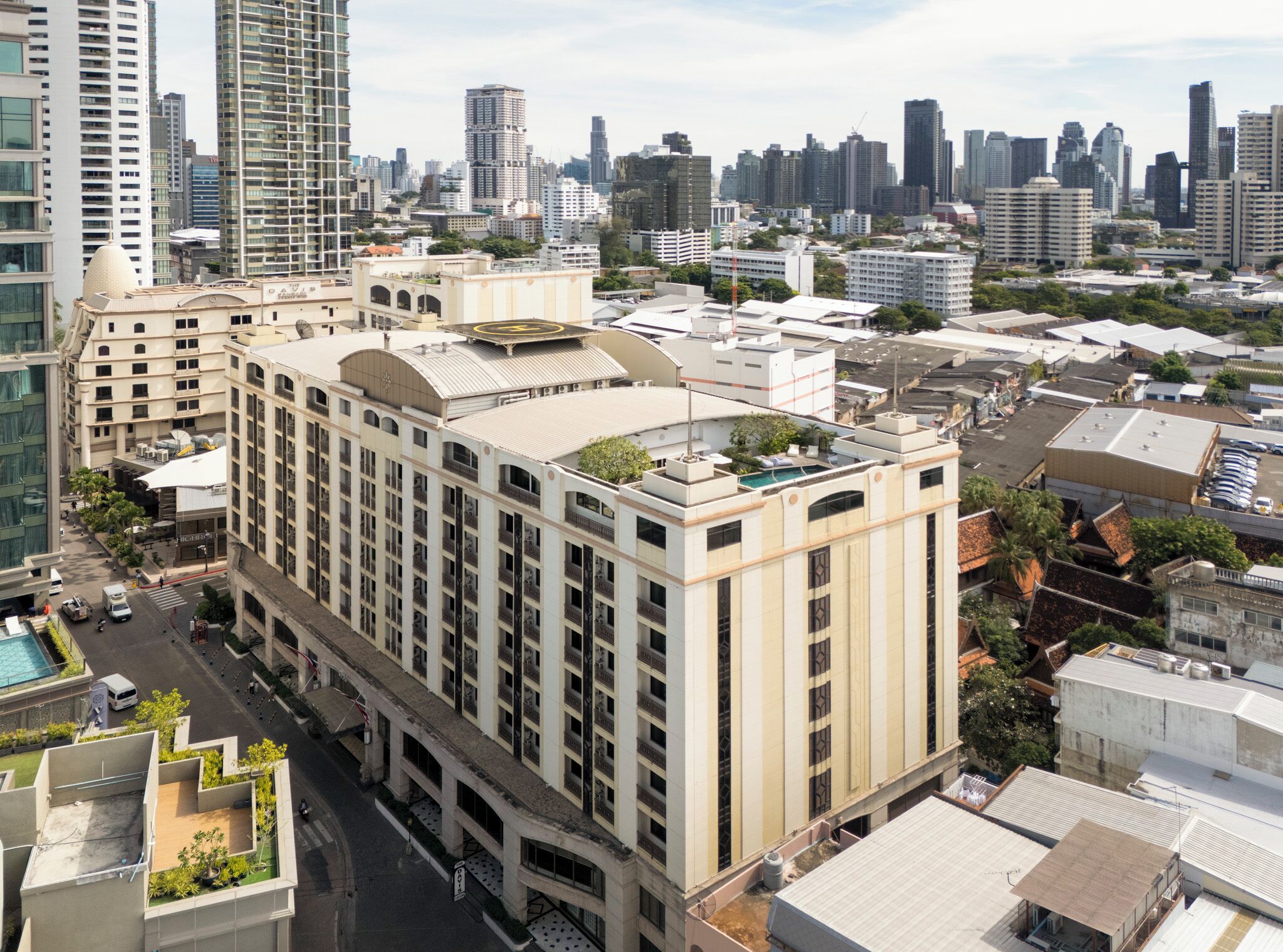 A high-rise hotel with multiple floors, a rooftop pool, and a city skyline in the background.