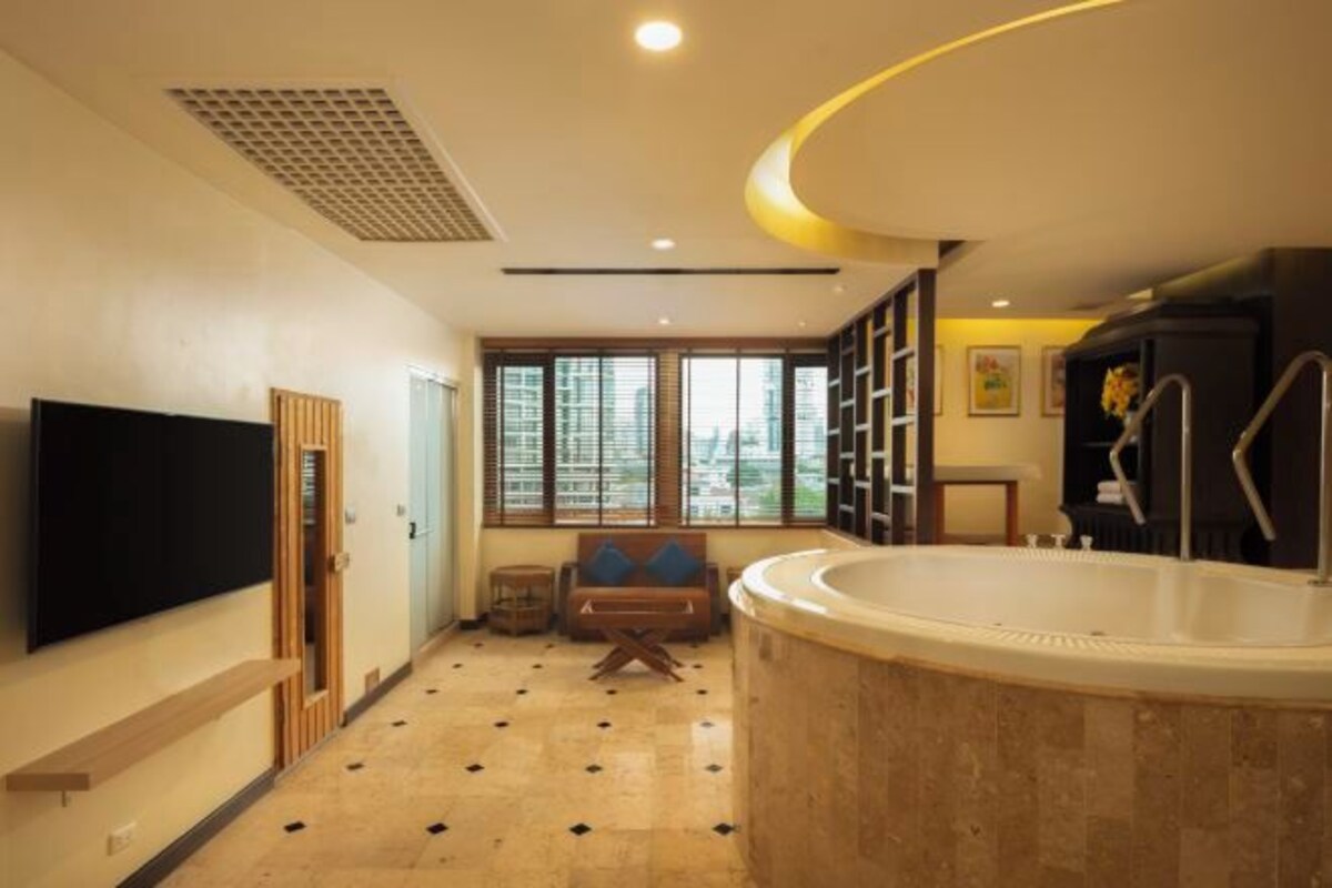 A modern bathroom with a bathtub, a large mirror, and a window providing a view of the city.