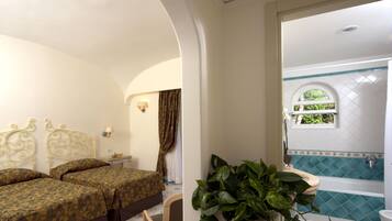 Ein Zimmer mit zwei Betten, einem Blumentopf, einem Badezimmer mit Badewanne und einem Fenster mit Blick auf Grünflächen.