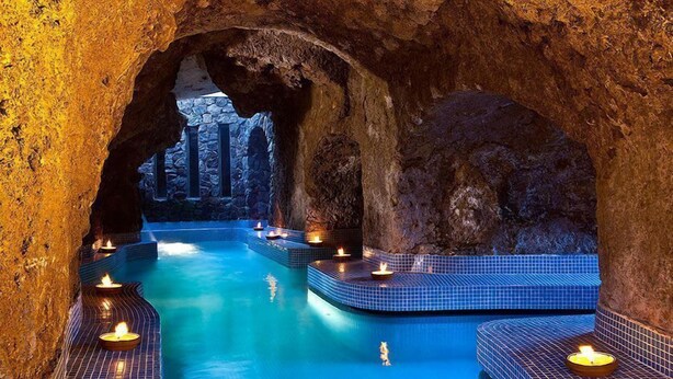 A spa area with a natural rock arch, a pool with blue tiles, and candles. - Grand Hotel Il Moresco & Spa (Ischia)